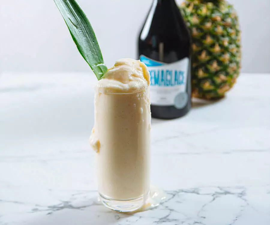 Grand verre de Pina Colada avec une bouteille de Cremaglace Vanille et un ananas