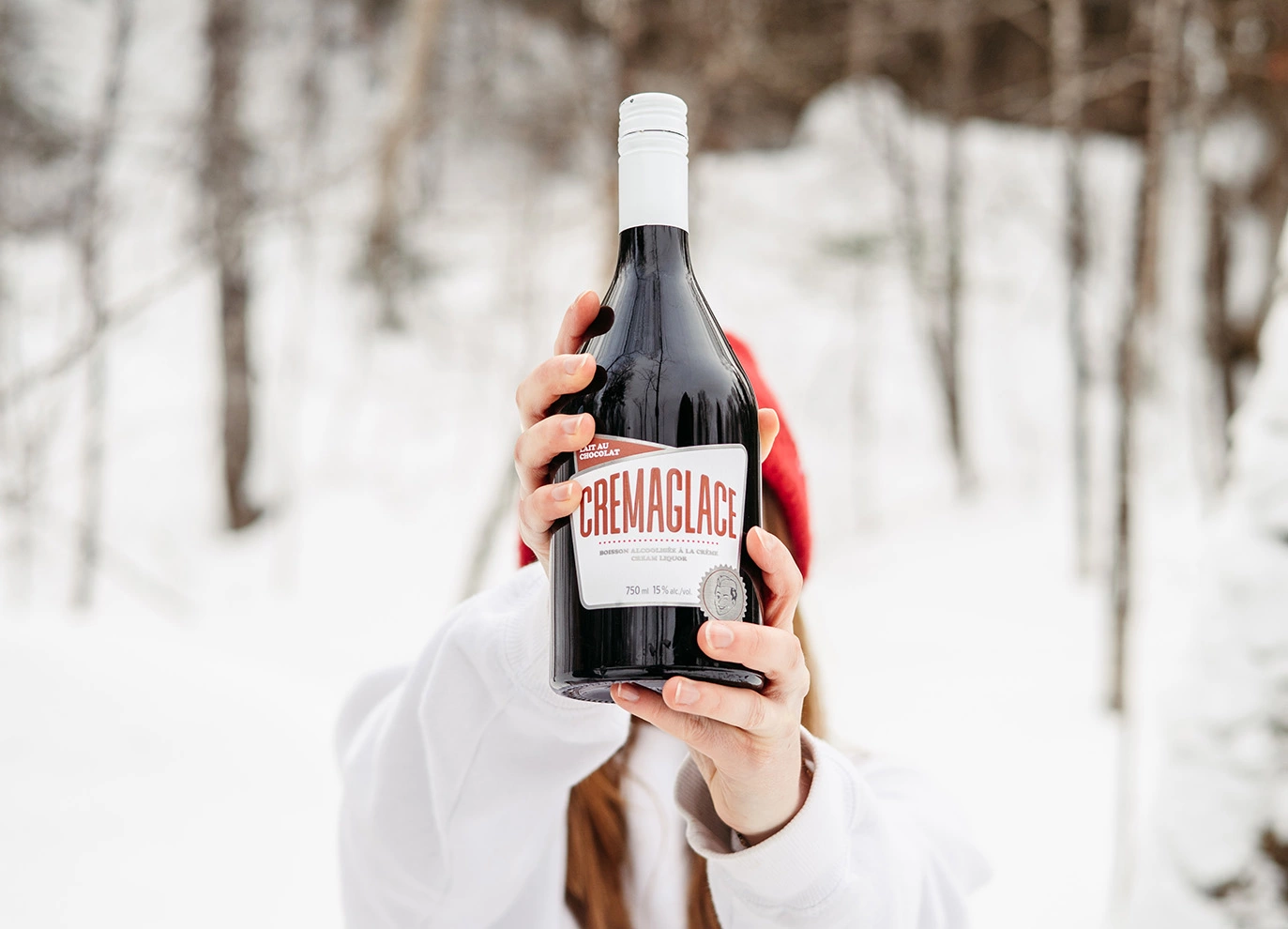 une femme qui tient une bouteille de Cremaglace Lait au chocolat dans la neige