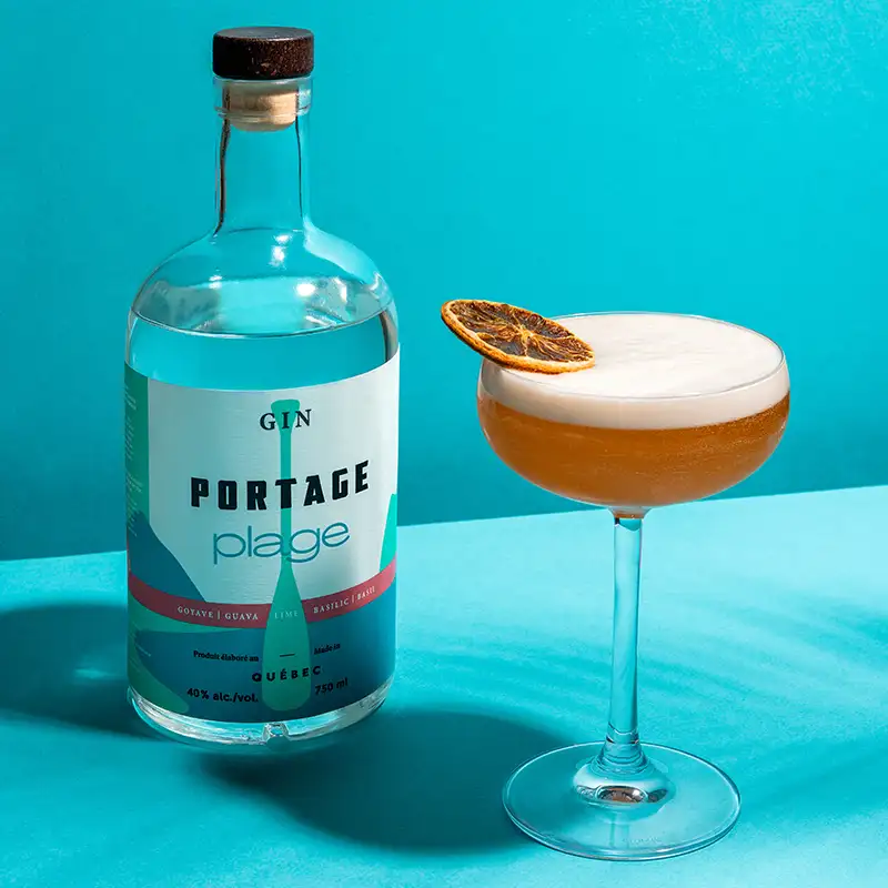 Un cocktail de Portage Plage sour avec une bouteille de Gin Portage Plage