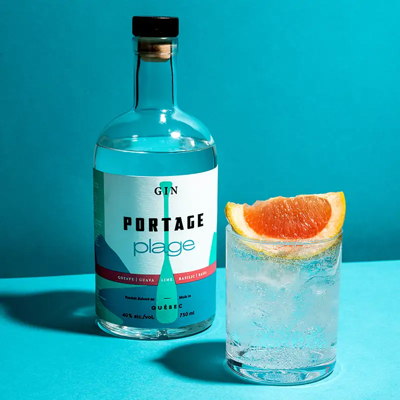 Cocktail Portage plage soda avec une tranche d'orange et bouteille de Gin Portage Plage